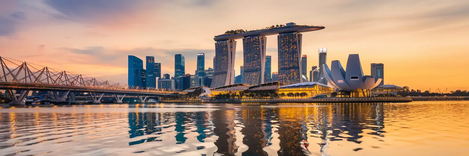 Marina Bay Sands and the Singapore skyline reflected in the calm waters of Marina Bay at golden hour