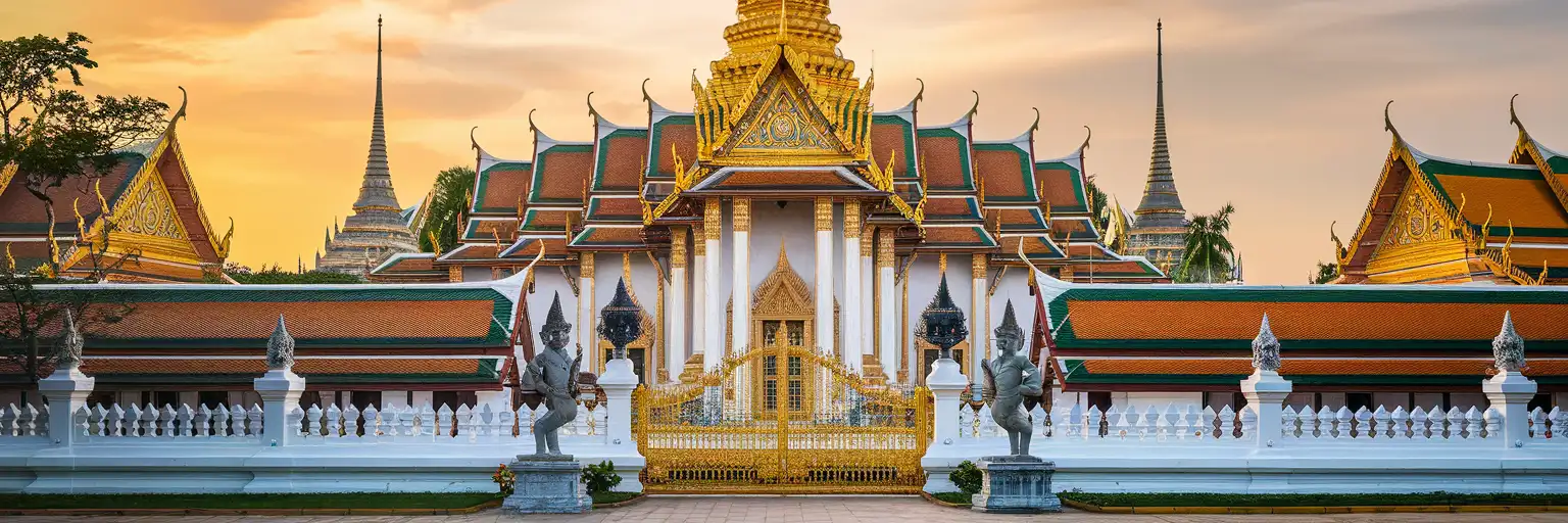 Golden spires and multi-tiered roofs of the Grand Palace complex in Bangkok at golden hour