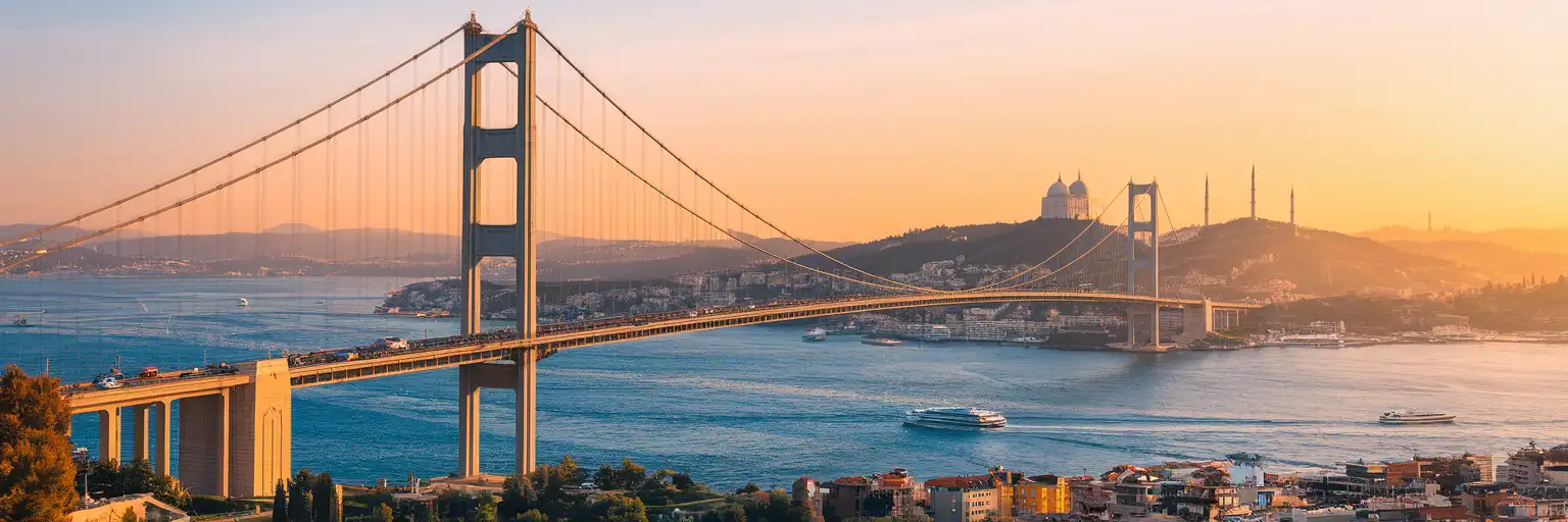 The 15 July Martyrs Bridge spanning the Bosphorus strait at golden hour with Ortaköy Mosque visible at the European shore