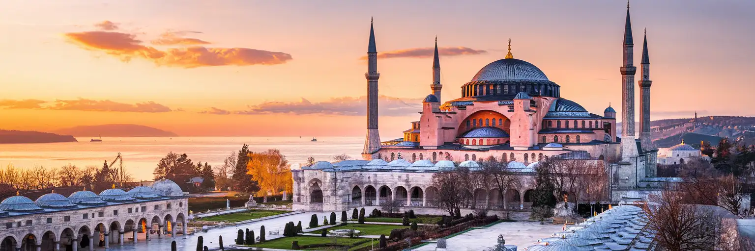 Hagia Sophia Grand Mosque in Istanbul at golden hour with its massive dome and minarets against a warm sunset sky