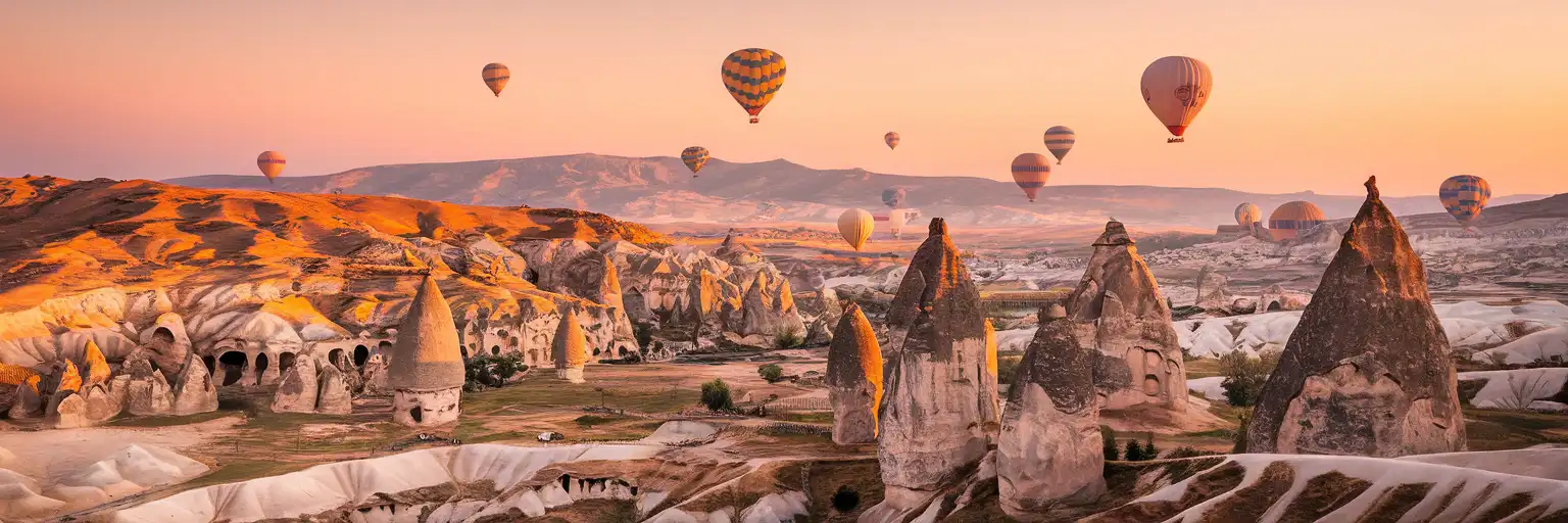 Hot air balloons rising over the fairy chimney rock formations of Cappadocia's Göreme Valley at golden hour