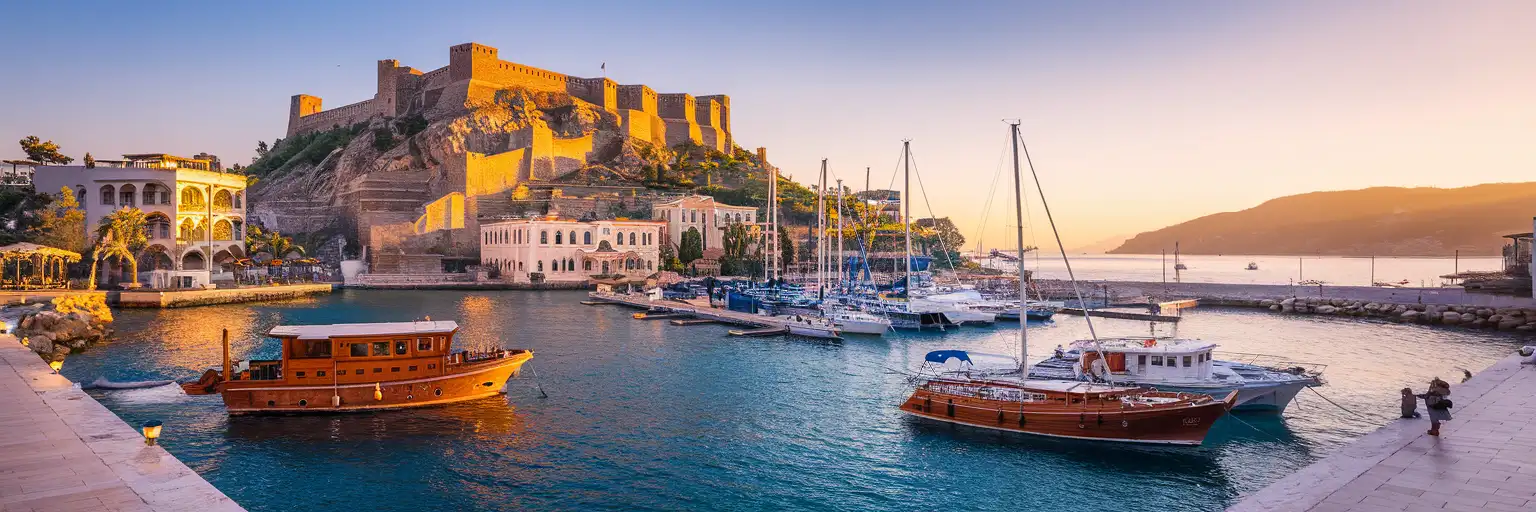 Marmaris Castle overlooking the harbor and marina at golden hour with pine-forested hills in the background