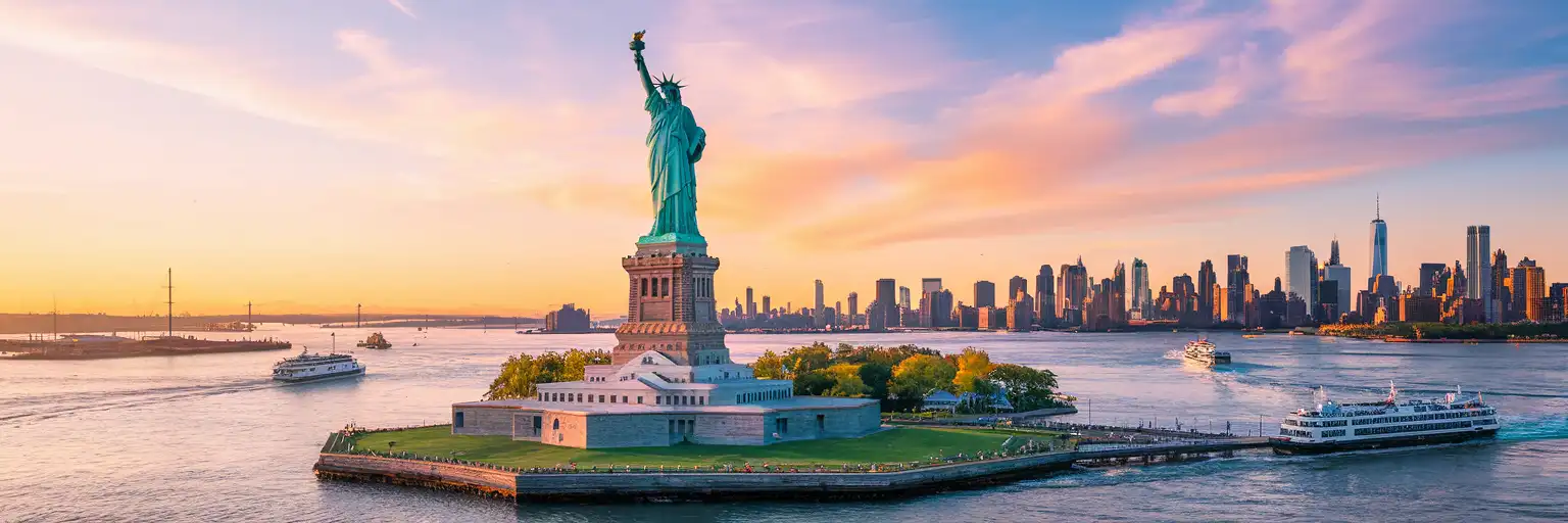 Statue of Liberty on Liberty Island at golden hour viewed from New York Harbor with Manhattan skyline in the distance
