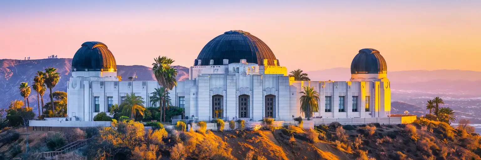Griffith Observatory Art Deco building with three copper domes overlooking the Los Angeles Basin at golden hour