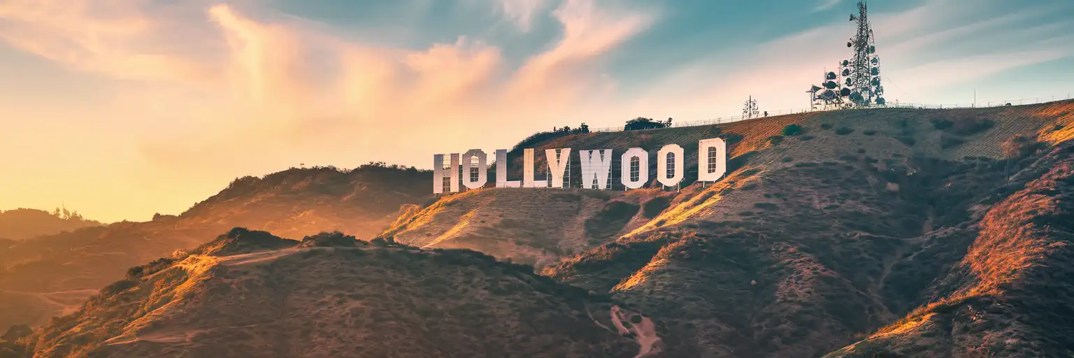 The iconic Hollywood Sign letters on Mount Lee bathed in golden hour light with the Santa Monica Mountains behind
