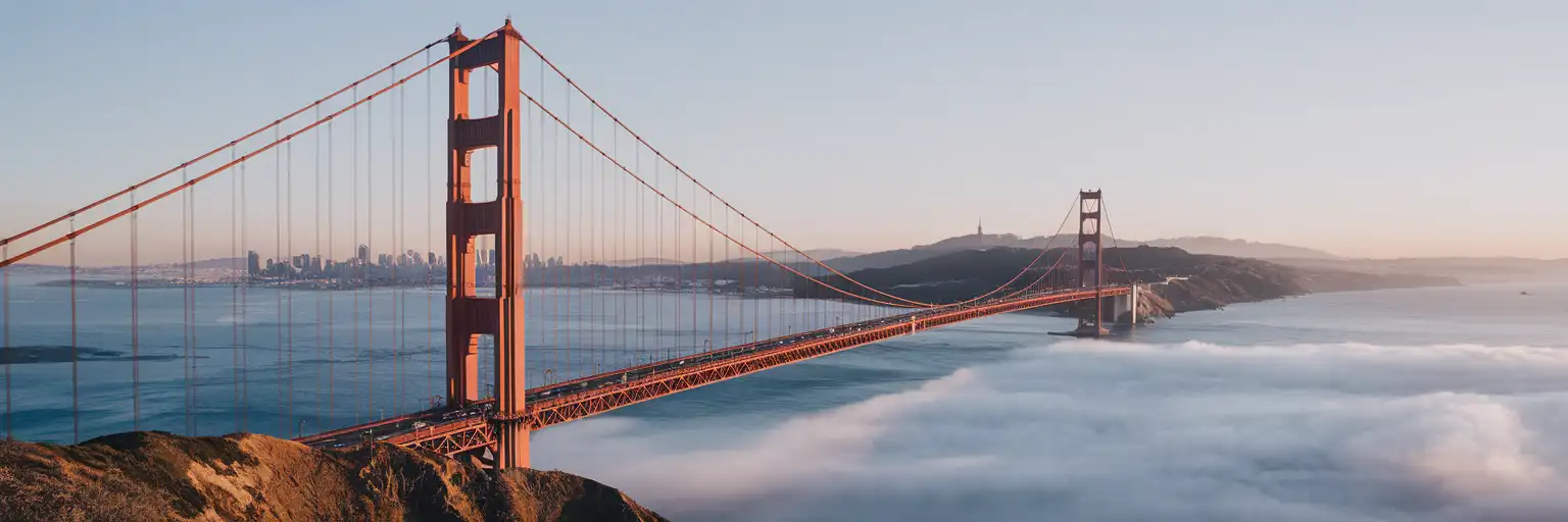 Golden Gate Bridge at sunrise with fog rolling beneath the deck and San Francisco Bay in the background