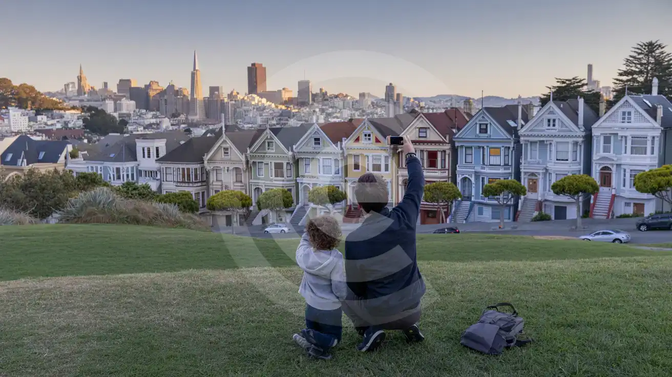 Family photographing the Painted Ladies Victorian houses at Alamo Square with the San Francisco skyline behind them