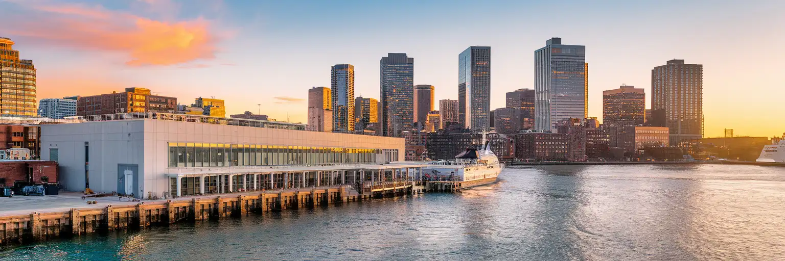 Exterior view of Flynn Cruiseport Boston on Boston Harbor at golden hour with the harborfront and Boston skyline beyond
