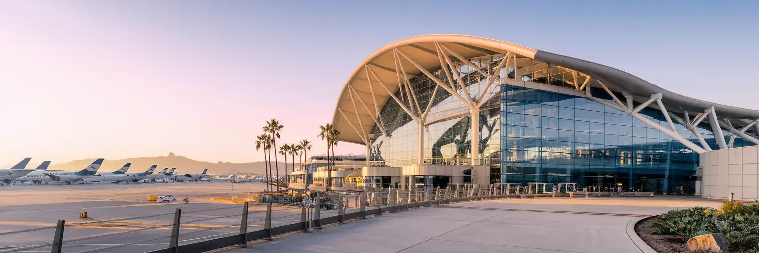 San Diego International Airport Terminal 2 exterior at golden hour with San Diego Bay and Point Loma in the background