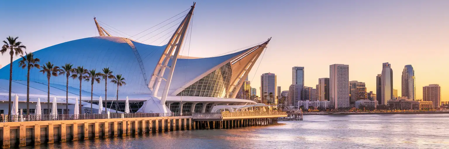 San Diego Convention Center sail-roofed exterior along Harbor Drive with downtown skyline at golden hour