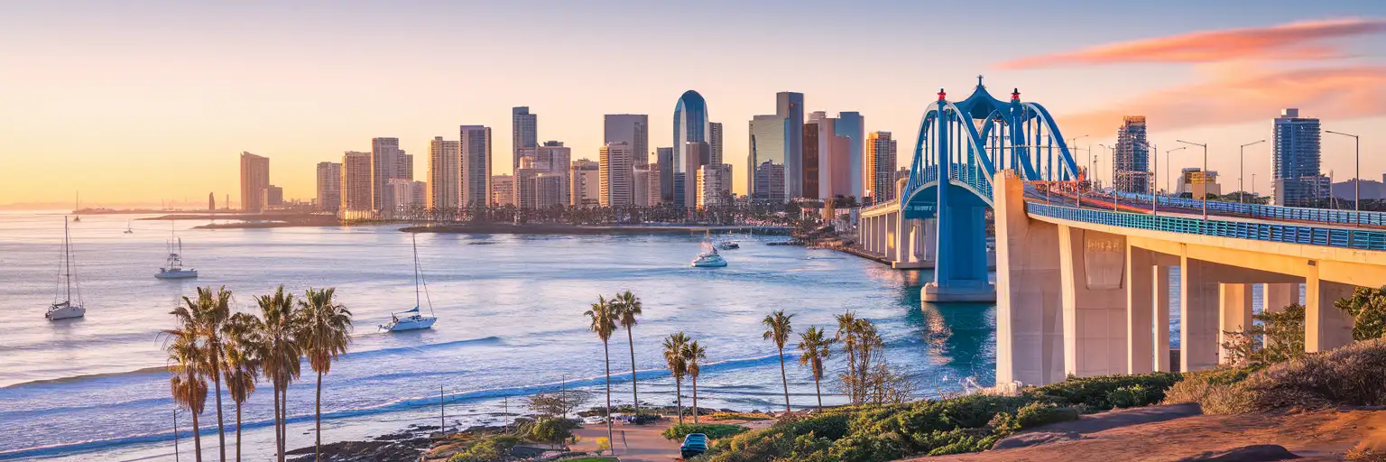 San Diego skyline and Coronado Bridge at golden hour with sailboats in the harbor