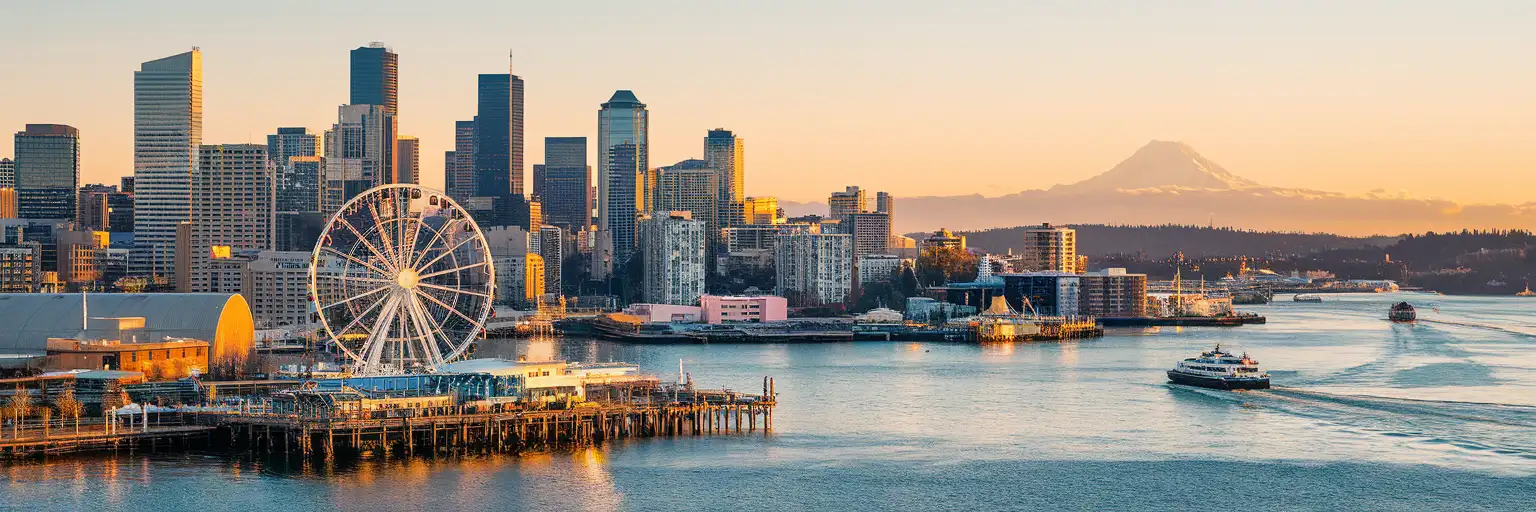 Golden-hour view of Downtown Seattle and the waterfront from Elliott Bay with the Seattle Great Wheel and skyline
