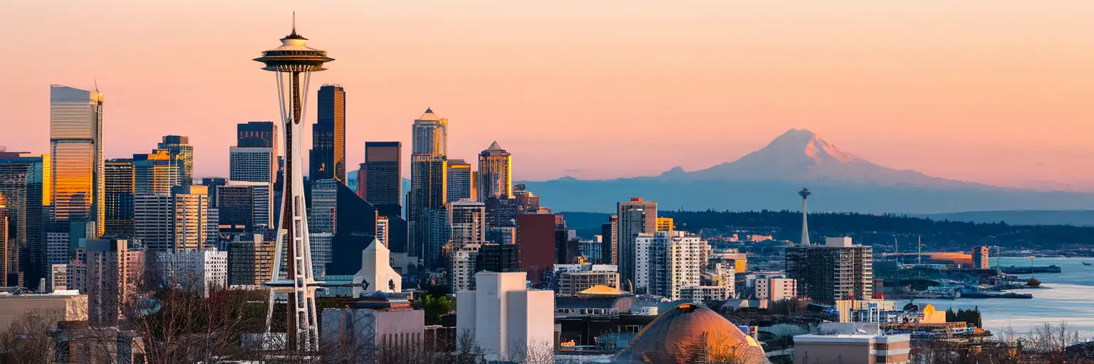 Seattle skyline featuring the Space Needle with Mount Rainier in the background at golden hour